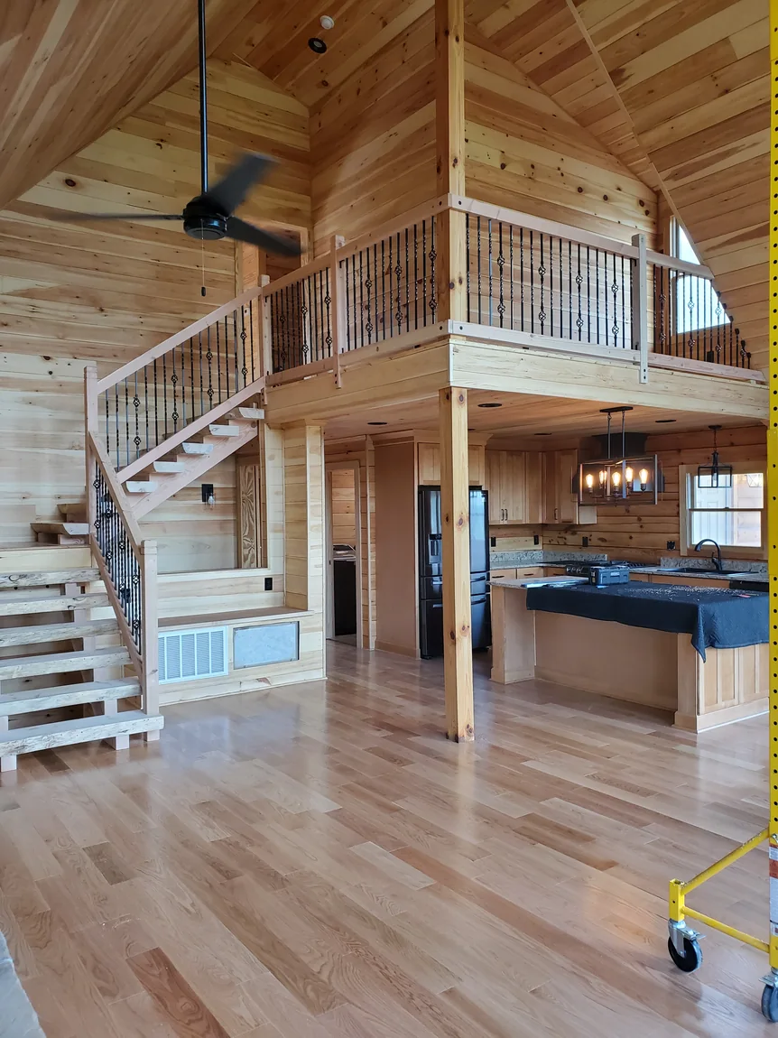 Custom log home interior with an open staircase, loft railing, and hardwood flooring
