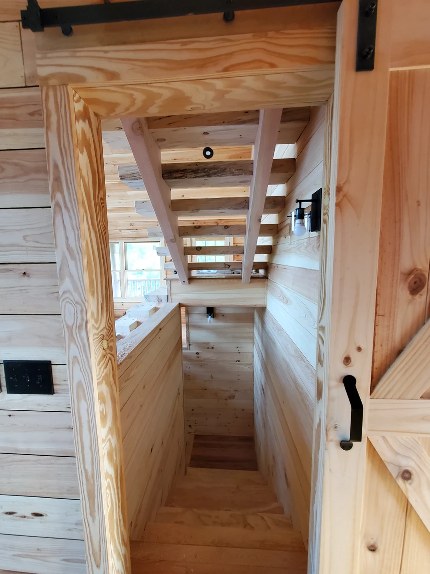 Custom log home stair landing with pine walls and sliding barn door hardware