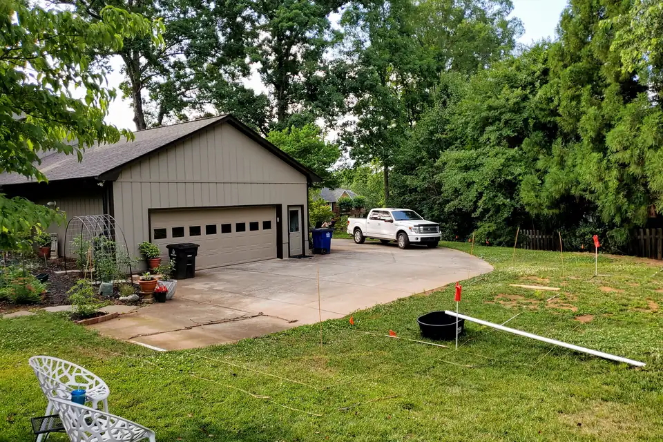 Backyard with a detached garage and string lines with marker flags staking out a new structure