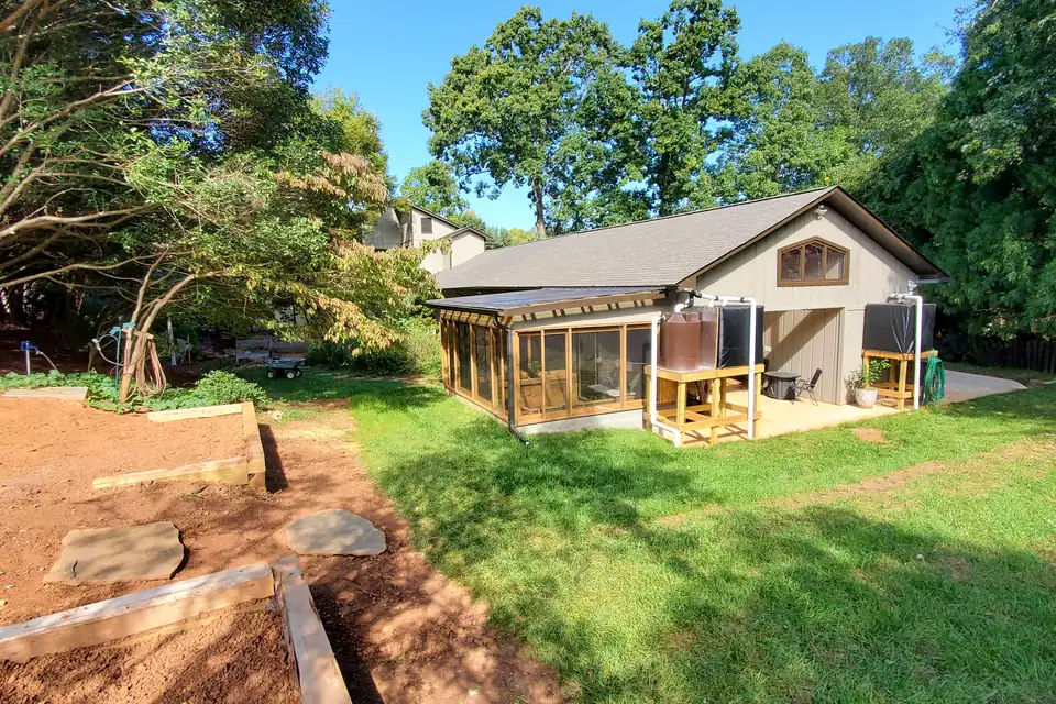 Glass-enclosed sunroom with a low shed roof added to the side of a board-and-batten sided building