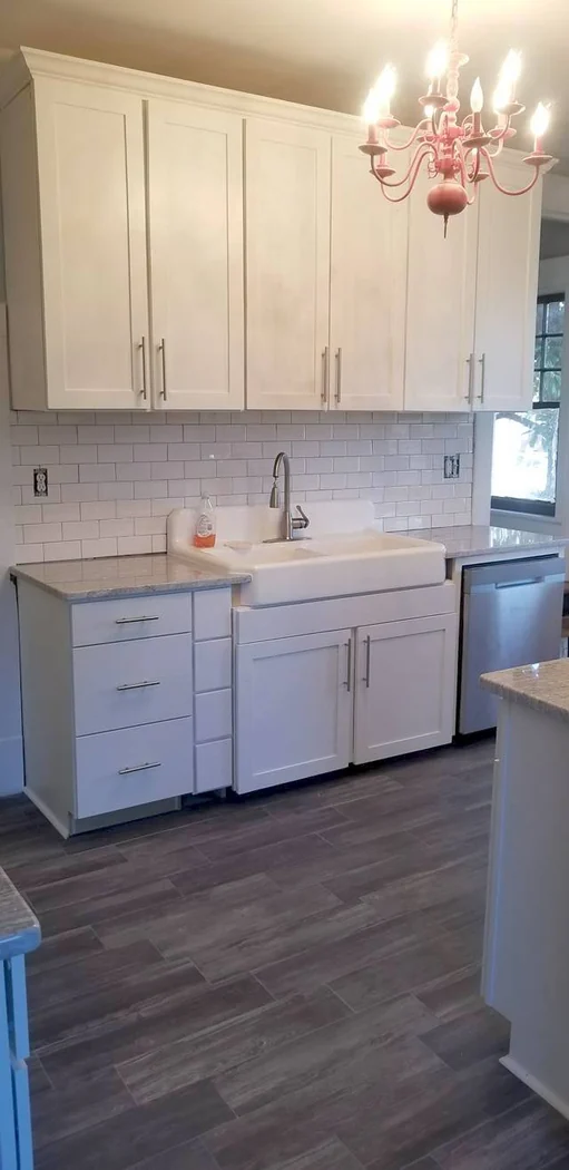 White shaker kitchen with apron-front farmhouse sink, white subway tile backsplash, and stone counters