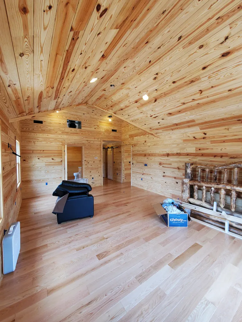 Room finished with knotty pine plank walls, vaulted pine ceiling, and new light hardwood flooring