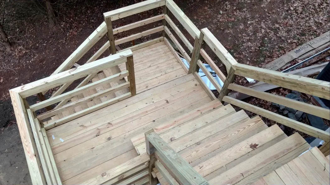 Deck under construction with pressure-treated decking down and railings and stairs going up