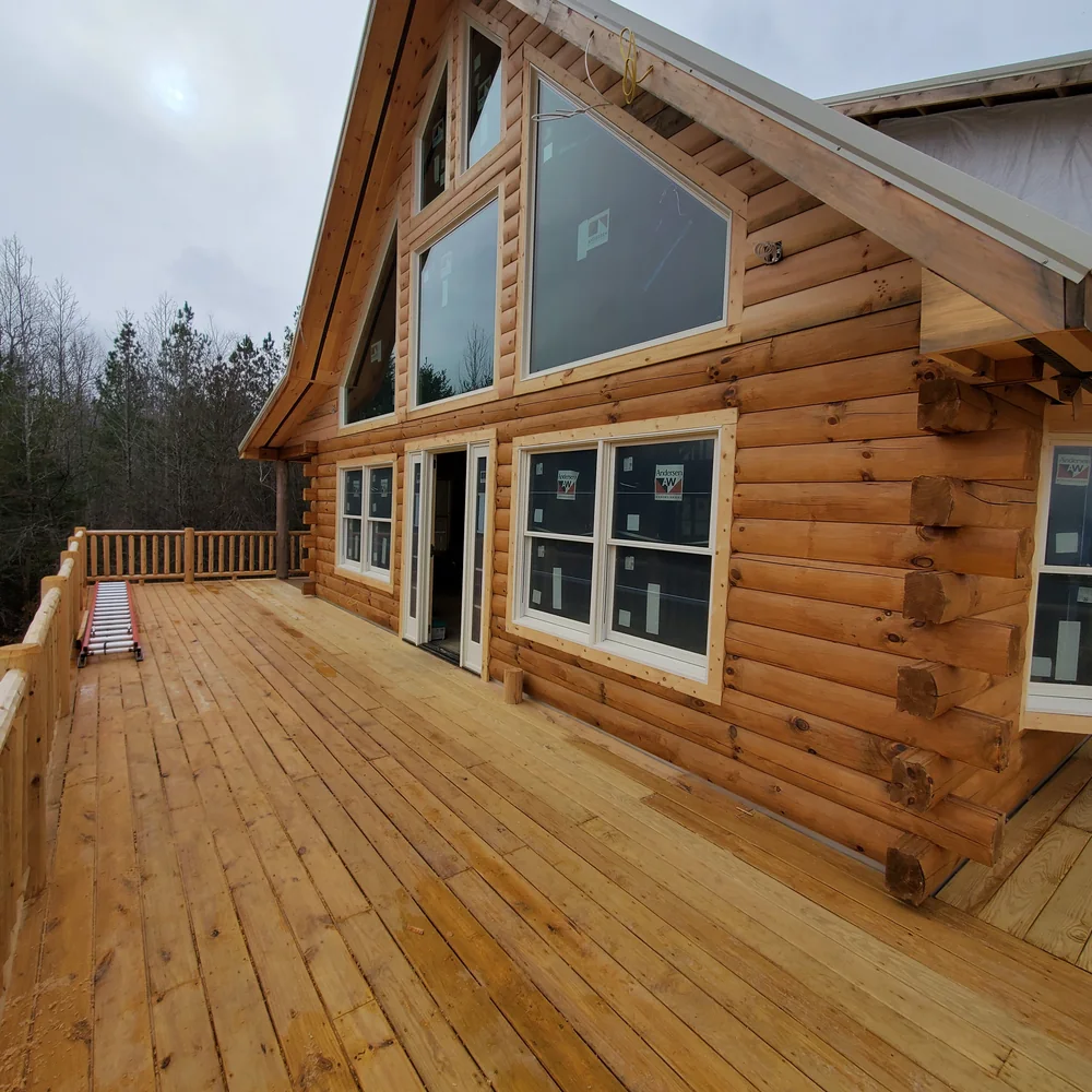 Custom log home with a large deck and floor-to-ceiling windows