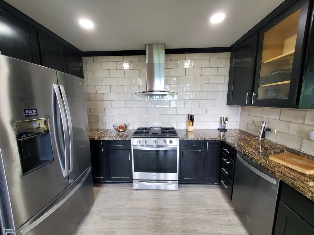 Kitchen remodel with dark cabinetry, granite countertops, and a stainless range hood
