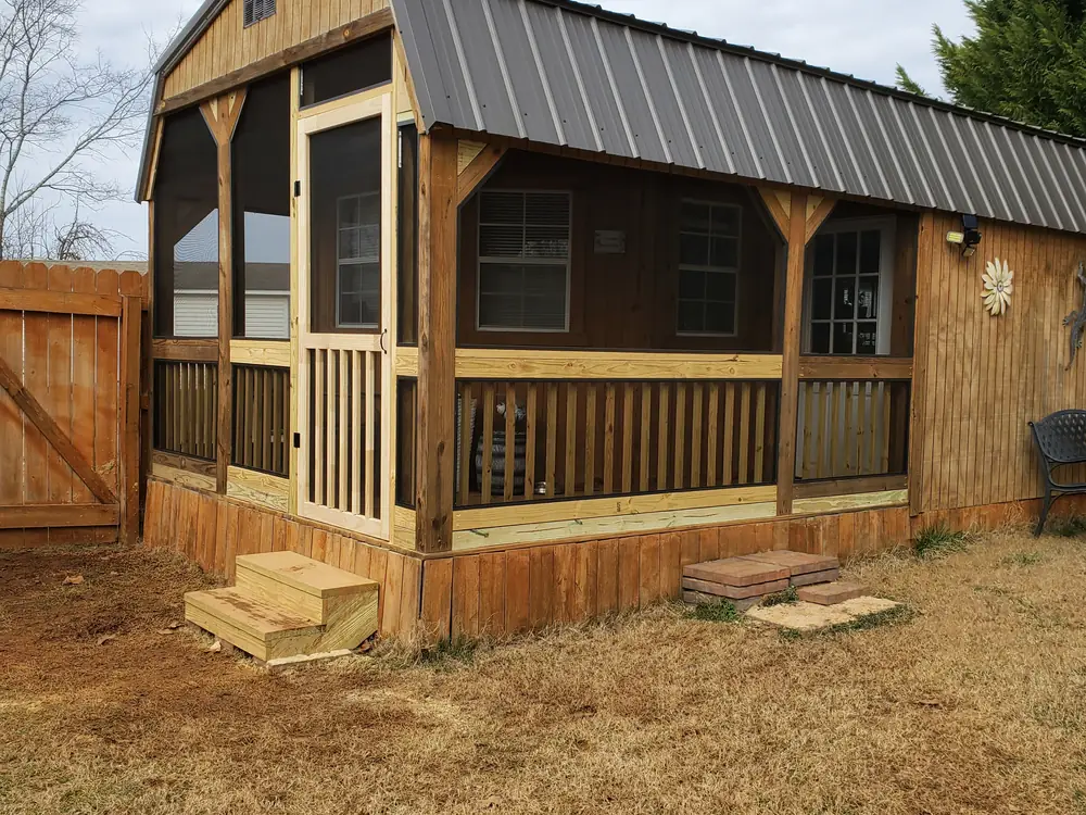 Screened porch on a barn-style cabin with a metal roof, stained wood siding, and new wood railings