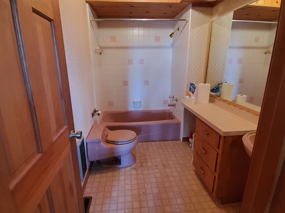 Dated bathroom with an old tub and vanity before remodeling