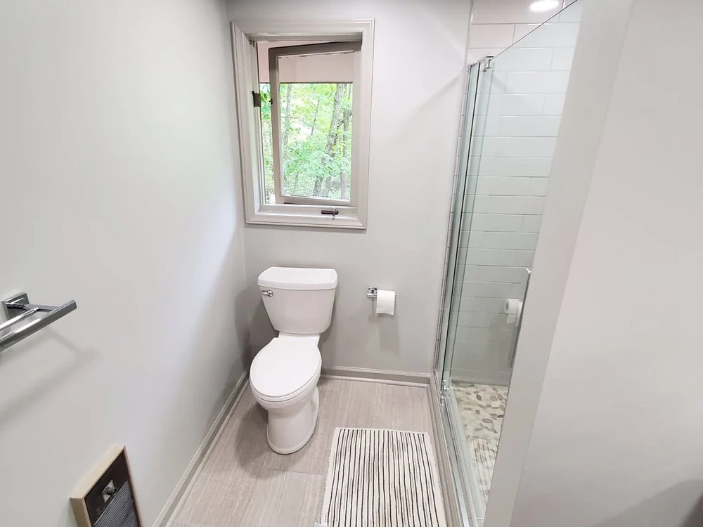 Finished bathroom with a glass shower enclosure, pebble-tile shower floor, and light plank flooring